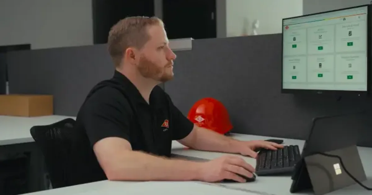 Construction professional reviewing Riskcast software at desk with hard hat