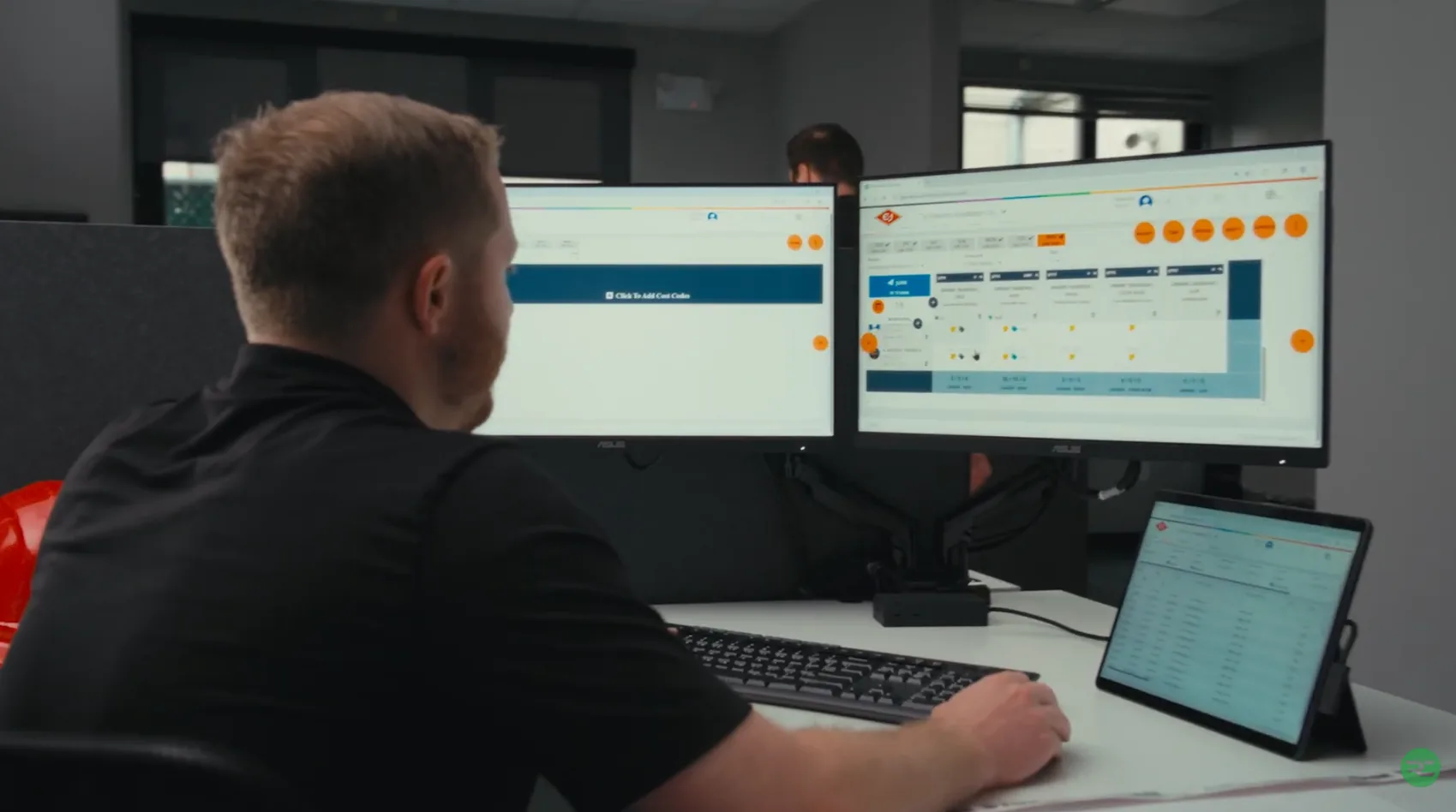 Construction professional reviewing Riskcast forecasting dashboard on dual monitors
